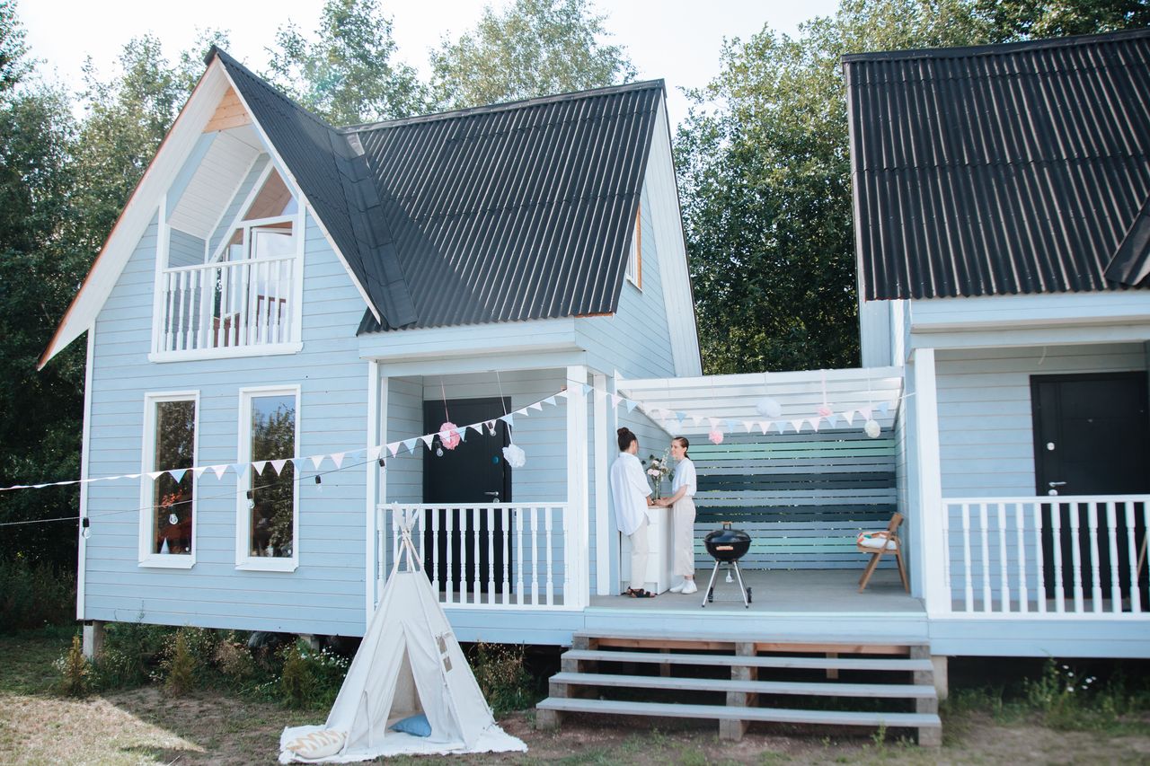 Outdoor party setup with decorations at a wooden house featuring two women on the patio.