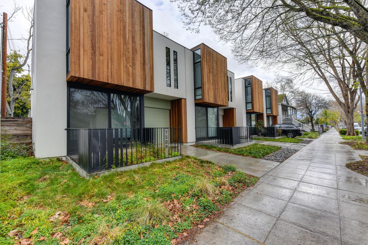 Contemporary suburban houses with wood accents in a tree-lined neighborhood.